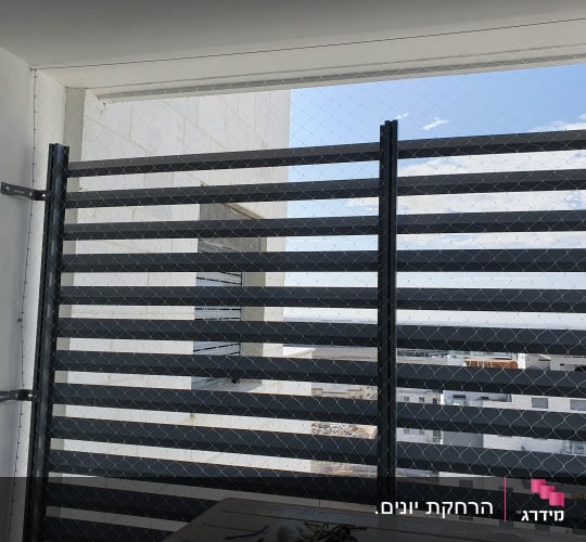 רשת מתכת מותקנת על גדר למניעת כניסת יונים